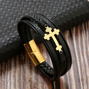 Detail view of handmade black braided leather bracelet with golden cross and magnetic clasp