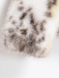 Close-up of fluffy faux fur material with gray and yellow leopard spots for women's coat