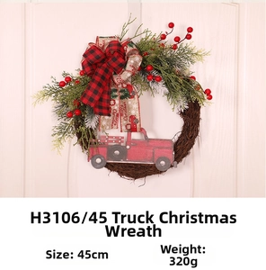 Detail of Christmas wreath with red truck and plaid bow on white wooden door