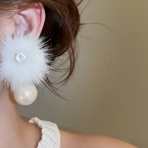 Detailed view of winter fur ball earrings with pearl drop and zircon center on model