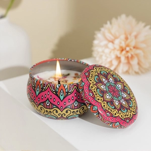 Close-up of burning scented soy candle in mandala tin with dried floral petals inside