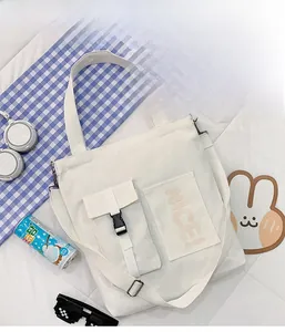 Flat lay of white canvas tote bag with functional double pockets and adjustable strap