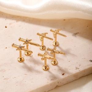 Macro view of six gold dagger stud earrings with crystal accents on silk fabric
