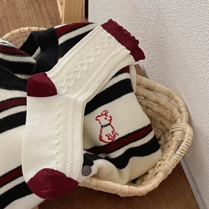 Detail of red and white knitted socks and striped sweater with cute dog embroidery