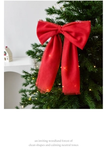 Illuminated red mesh bow with LED string lights on a green Christmas tree branch