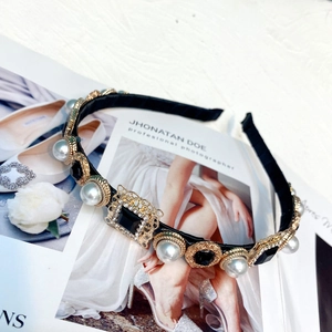 Close-up of baroque headband featuring black gemstones and pearls on a vintage gold base