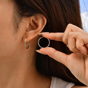 Detailed view of silver stainless steel hoop earrings with hidden hinge closure on ear