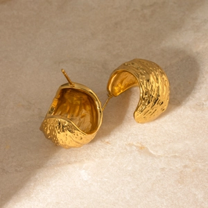 Detail of 18k gold plated chunky C-shaped earrings with unique hammered metal texture