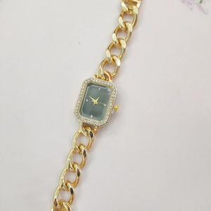Detail of a gold-tone women's watch with an octagonal rhinestone-inlaid dial and thick chain