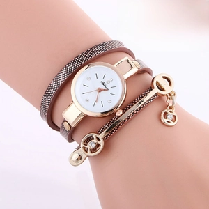 Close-up of brown quilted leather wrap watch with gold metal bars and crystal charms