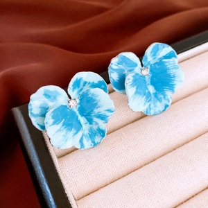 Blue enamel iris flower stud earrings with central zircon inlay on velvet display