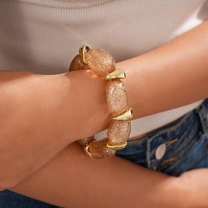 Detail of amber acrylic beaded bracelet with gold glitter and irregular metal links