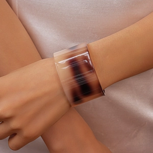 Detail of amber tortoiseshell acetate bangle on wrist with smooth polished finish