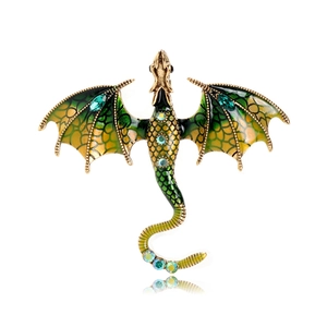 Macro detail of vintage gold dragon brooch with green enamel wings and rhinestones