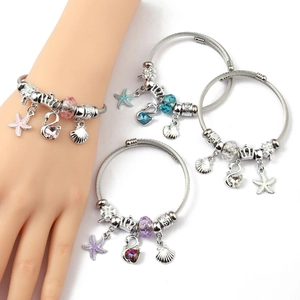 Detailed view of silver wire bangles with crystal swan, crown, and heart pendants