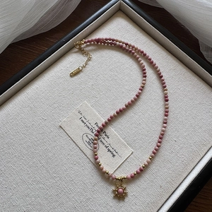 Close-up of pink beaded sun pendant necklace with natural rhodochrosite and gold accents