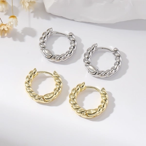 Chic twisted metal hoop earrings in gold and silver finish on a minimalist white display