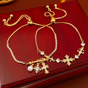Détail du bracelet doré ajustable avec croix en diamant étoile et breloques perles