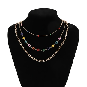 Close-up of triple-layered gold necklace with colorful stars and beads on black bust