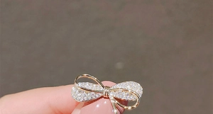 Détail macro d'une broche nœud dorée avec micro-pavé de zircons blancs de luxe