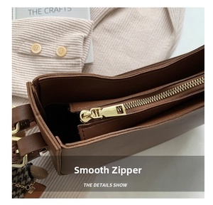 Close-up of smooth gold metal zipper closure on brown leather shoulder bag detail