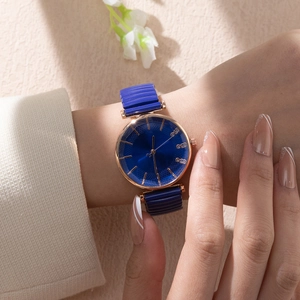 Dettaglio di un orologio con quadrante blu e indici in oro rosa sul polso di una modella