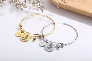 Close-up of gold and silver wire bracelets with heart charms and Grandma engraving