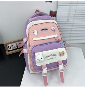 Detail of purple-pink canvas backpack with cartoon badges and plush bunny keychain charm