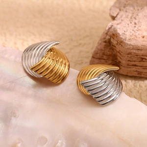 Macro view of gold and silver textured striped fan earrings on a natural background