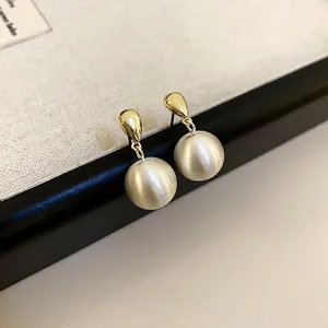 Boucles d'oreilles élégantes en métal brossé doré avec clou goutte et perle satinée