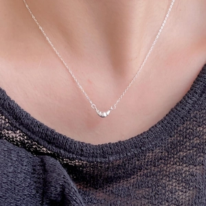 Close-up of a minimalist 925 sterling silver croissant pendant necklace worn by a model