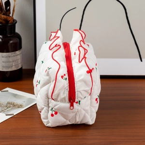 Détail de la trousse de maquillage matelassée blanche avec volants rouges et motif cerises