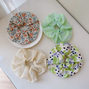 Close-up of four floral print chiffon hair scrunchies in various pastel colors