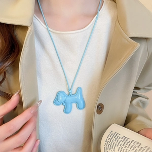 Détail du collier avec pendentif chiot bleu porté par un mannequin sur un trench-coat chic