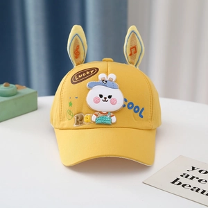 Detail of yellow baby baseball cap with plush bunny ears and cute cartoon patches