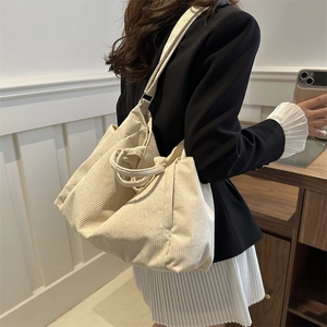 Minimalist corduroy tote bag in cream white color carried by model in casual office setting