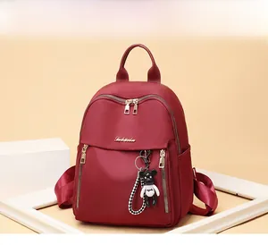 Close-up of deep red oxford backpack with gold zippers and a cute bear keychain