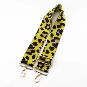 Detail of adjustable leopard print bag strap with gold metal buckles on white background