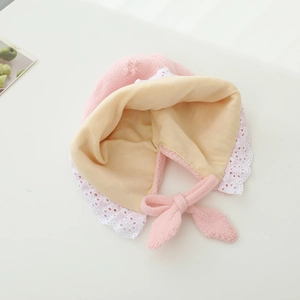 Detail of pink knitted baby bonnet showing delicate white lace trim and soft lining