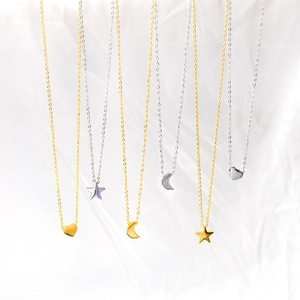 Minimalist gold and silver stainless steel heart star and moon pendant necklaces on white fabric