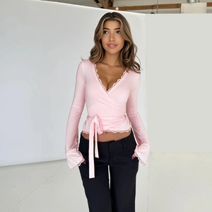 Dettaglio del top rosa con pizzo, scollo a V e lacci regolabili in vita