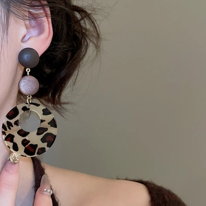 Close-up of bohemian leopard print resin hoop earrings worn by a fashion model