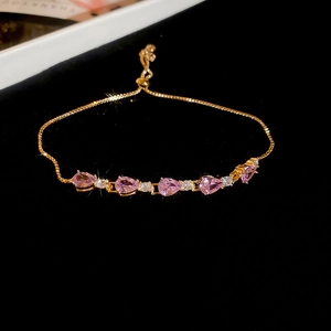 Detail of adjustable gold bracelet featuring pink pear-cut zircon and white accents