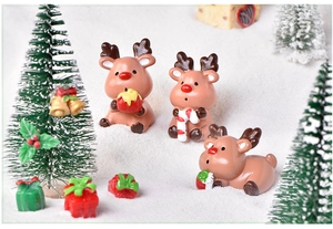 Close-up of three miniature resin reindeer figurines in a snowy Christmas micro landscape