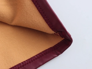 Detailaufnahme der Nähte an weinrotem Leder und beigem Fleece-Futter des Ensembles