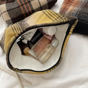 Detailed view of yellow plaid wool makeup bag interior with various cosmetics