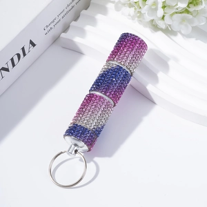 Close-up of a three-section gradient rhinestone pill bottle keychain on a white desk
