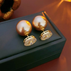 Détail de boucles d'oreilles double face avec perle dorée et fleur en zircon brillant