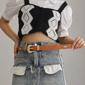 Detail of brown leather belt with gold floral buckle and ethnic embroidery on model