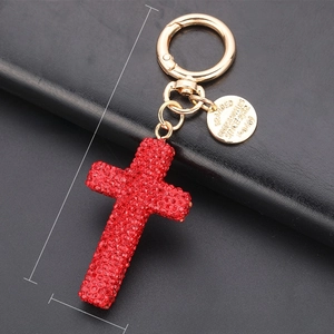 Close-up of sparkling red rhinestone cross keychain with golden chain and clasp